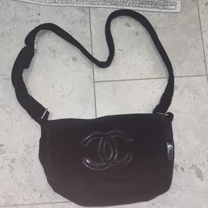Chanel axelremsväska  - Axelremsväska Chanel (troligtvis inte äkta) som jag köpt second hand. I Teddy material, så fluffig och söt. I använt skick men spännen, knappar, dragkedjor funkar hur bra som helst. Rymlig dessutom. Hör av dig vid fler frågor!