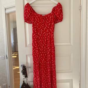 En blommig röd klänning i storlek 36 från & other stories i modellen Flowy puff sleeve Midi dress. Använd 1 gång. 