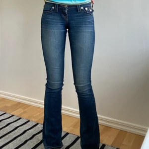 True Religion lågmidjade bootcut jeans - Coola lågmidjade bootcut jeans från True Religion i mycket bra skick, storlek 23 som passar perfekt på mig som är 174 cm. Köparen står för eventuell frakt