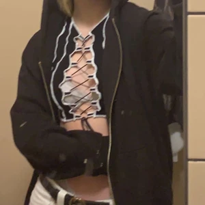 Cool svart t-shirt - En cool svart t-shirt med band som går att spänna och lossa. Vita sömmar, annars är den helsvart. Köpt på hm för något halvår sedan. Använd runt 4 gånger max så den är i bra skick! 