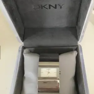 Jättefin klocka från DKNY, Donna Karan, som ett silverarmband. Urtavlan i ljus silver. Använd några gånger men i bra skick, lite småreparationer men inget som stör utan blir av normal användning. Batteriet kan behövas bytas. Fungerar såklart. Inköpt på Stjärnurmakarna i Täby C för 2500:-, kvitto finns. Självklart äkta, kommer i jättefin ljusgrå originalbox med extra länk om man behöver länga den.  Skickar med posten mot porto, fri frakt gäller upphämtning vid Stadion /Tekniska eller Täby c Stock