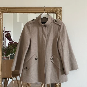 Beige kappa - Beige poncho-liknande kappa från Zara. Ärmarna är vida och finns både dragkedja och knappar. Väldigt gott skick, knappt använd