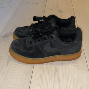 Svarta Nike AirForces 1, brun/gul sula - Säljer ett par svarta Nike AirForces 1 skor med brun/gul sula. Storlek 37,5. Material: mocka. Skorna är ganska använda samt lite slitna invändigt på höger sko, & därför är priset lågt. Ingen retur. Kan mötas upp i Stockholm. Pris: 200kr (+frakt ifall så behövs).