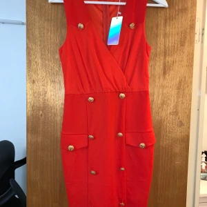 Röd klänning med gulddetaljer , hollies - Helt ny från Hollies, bara testad sjukt bekväm. Prislappen sitter kvar, köpt för 1100. Klänningen på mig är till knäna och jag är 158