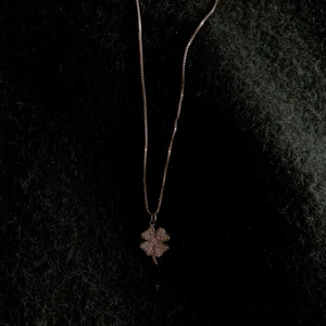 Halsband, silver - En lucky charm (fyrklöver som motiv) med fina silvriga ”diamantstenar” i. Relativt kort. Som nytt.