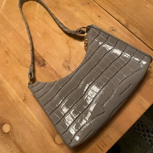 Axelremsväska  - En snygg väska i grått med ormskinsimitation. Bra skick, sällan använd. 