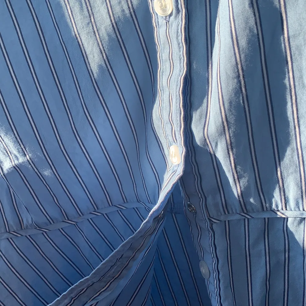 En jättefin ljusblå blus GANT blus med färgerna ljusblå, mörkblå och vit i randmönster. Längst ner på blusen går den ut som en ”kjol” (det är ingen kjol utan den är kort och sitter som en vanlig tröja/blus). Kom ihåg att höra av er för mer information eller bilder vid intresse av köp :). Blusar.
