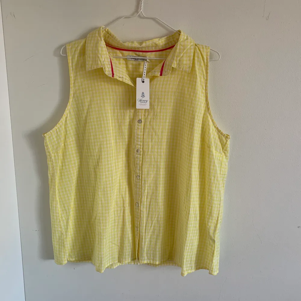 En oanvänt ärmlös skjorta i fint sommrigt gul färg. Köpt för ett par år sedan men inte kommit till användning.. Skjortor.