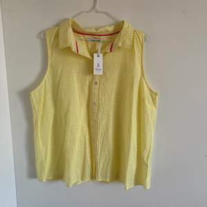 En oanvänt ärmlös skjorta i fint sommrigt gul färg. Köpt för ett par år sedan men inte kommit till användning.