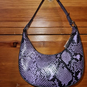 Liten lila väska  - Liten väska från Asos. Helt oanvänd. Storlekarna och frakten är på ett ungefär. Köparen står för frakten. Buda i kommentarerna 💜