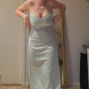 Balklänning - Grön balklänning med öppen rygg i satin. Jag är 165 lång, men fungerar för längre personer, modellen på nakd bilden är 173 cm. Säljer den då jag inte kommer få användning för den. Den är heller inte använd någon gång, lappen är kvar:) köpt för 599:-