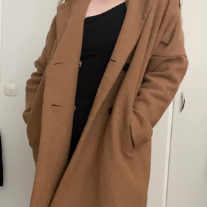 Camel kappa från Lager 157 - Superfin kappa från Lager 157. I storlek XL men passar oversize om du har L. Jättesmickrande passform med drop shoulder, trots oversize så ser den skönt avslappnad ut och inte som ett tält som de lätt blir annars. Obetydligt använd. Dom få gånger jag använt den har jag fått massa komplimanger! Synd bara att jag aldrig får användning av den.