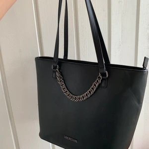 Äkta moschino väska - Rymlig väska, får plats med det mesta. Mycket bra skick, inga defekter som hål, skrapningar m.m. Köpt för 1700kr. Betalning sker via swish. Dustbagen ingår.