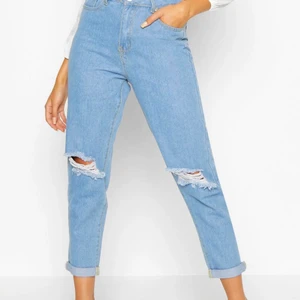 Ljus blåa slitna mom jeans - Detta är slita ljus blåa mom jeans från hemsidan boohoo, jätte fin och hållbar kvalité. Dom är endast testade men aldrig använda pågrund utav att det var fel storlek för mig, vilket då blir anledningen till att jag säljer dessa jeans. (Frakten är inte gratis den diskuteras priv) Storleken är 44/XL