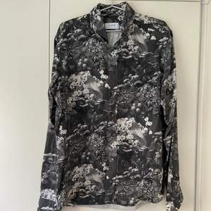 En sparsamt använd skjorta som är grå med mönster på. Köparen står för frakt.