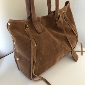 Mockaväska - Rymlig väska i brun äkta mocka. Går att stänga med magnetknapp. Tillhör även en necessär. Köpt för 700 kr. Endast använd 2-3 gånger.