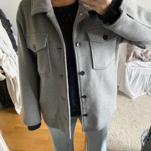 Grå skjortjacka/kort kappa i ullmix - Superfin grå, lite oversize skjortjacka/kort kappa från KappAhl. Ullblandning. Storlek S men passar även större/mindre beroende på önskad passform. Köpt förra hösten, men aldrig använd. Säljes pga används inte. Jättefin och perfekt till hösten/vintern🍁💛