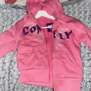 Miss jeans kofta  - Tjock/varm rosa kofta med luva. lila text med paljetter/diamanter på. Bra skick och med rosa fluff inuti. 