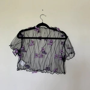 Unik crop top - Säljer denna svarta crop top som är i mkt bra skick! Förutom att den är i princip genomskinlig har den även lila fjärilar som är fastsydda utanpå plagget. Unik! Den passar mig som är S men kan även passa andra storlekar så som XS-M.