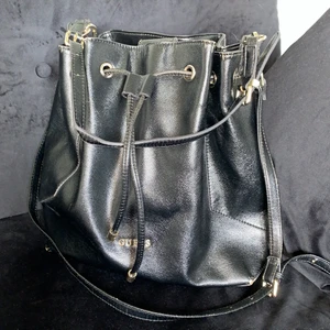 Svart väska från GUESS - Axelremsväska från GUESS. Svart skinnimitation mdd gulddetaljer.