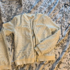 Vit jacka - Säljer denhär fina tunna vita jackan med guldiga detaljer, den används aldrig och har använts ett fåtal gånger så den har en fläck inuti som inte syns annars är den helt som ny💕✨