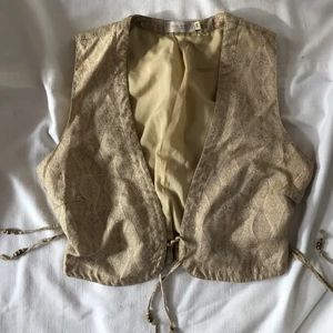 Guldig väst - Söt liten gullig väst i en guldig färg. Gott second hand skick. Passar bra på mig som vanligtvis bär S i toppar. Köpare står för 48kr frakt. Perfekt som layeringplagg nu till hösten!