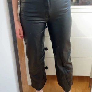 Läderimitation byxor - Ett par supersnygga läderimitation byxor från H&M!! Jag är 1,66 och de är lite korta för mig. Nypris ca 300, slutsålda i nästan alla storlekar på hemsidan. De är vida, raka och högmidjade. Använda många gånger men inga defekter eller så. De är ganska tajta i midjan och korta i benen. De skulle nog passa dig som är runt ca 1,55-1,60 perfekt, men kanske även för kortare personer. OBS möts inte upp!!