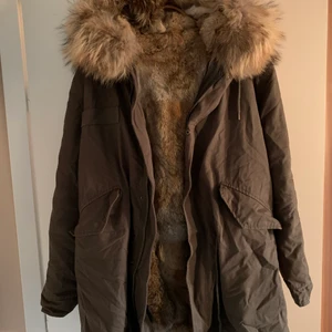 Jacka med äkta päls - Snygg jacka i kaki (brun/grön) med avtagbar äkta päls på insidan. Finns dragsko i midjan så man kan dra åt om man vill. Knappt använd och köpt på gamla Fiorucci i Göteborg. Finns ingen storlek men uppskattar till storlek M. Men kan passa S-L beroende på hur man vill att den ska sitta. 