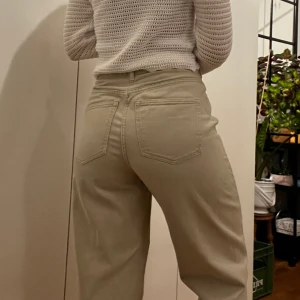 Mom jeans från H&M, strl 38 - Snygga beiga mom jeans i storlek 38 från H&M. Har två små hål på insidan av midjan där jag satt i ett skosnöre för att anpassa midjan men det går lätt att ta ut och hålen syns såklart inte på utsidan. Sparsamt använda. Köparen står för frakten!
