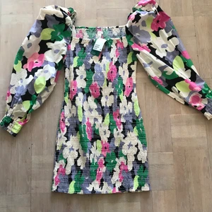 H&M blommig klänning - Går ovanför knäna. Krinklad med puffiga ärmar. Helt ny med prislappar.