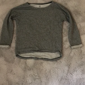 Grå långärmad  - En grå långärmad tunn topp från H&M. Toppen har uppvikta ärmar och är lite kortare i fram. Den är använd ganska mycket men är fortfarande i väldigt bra skick.