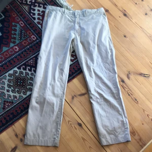 Polo Ralph Lauren Chinos - Supersnygga Polo Ralph Lauren chinos i beige färg. De är väldigt tunna och luftiga och passar perfekt till sensommaren eller hösten. Storleken är 38/34 och passar perfekt om du vill ha ett par baggy chinos. De har ingen knapp därframme utan den sitter istället på sidan, se sista bilden De är använda men i fint skick