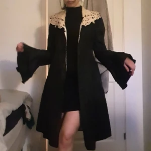 Ca 110 år gammal sidenkappa, strl M - Edvardiansk kappa söker kärleksfullt hem.           Otrolig sidenkappa från ca 1910-tal. I fint skick med tanke på åldern. Slitningar finns främst längst med ena sidan av ryggen och under ena ärmen (skickar bilder vid förfrågan), men i sin helhet är den inte märkbart sliten.  Material: taftsiden (yttertyget), satinsiden (innertyget), battenburg-spets  Passar S-M.             Byst: 86 cm Midja: 81 cm Höfter: öppen Längd: 109 cm Axlar: ca 35 cm Armlängd: 71 cm