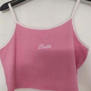 Croppat linne - Rosa, kort linne med "Cute" broderat fram! Den har en pytteliten mörkrosa fläck på högersidan som knappt syns, annars helt defektfri ✨💗