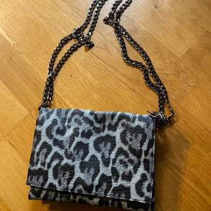 Väska - Handväska med leopardmönster och kedja. Väskan har flera mindre fack och är perfekt som mindre handväska. Använd 2 gånger så som ny. Skickas mot frakkostnad, köparen väljer själv om hen vill ha spårbar frakt eller med frimärken. Samfraktar gärna om du hittar något mer du vill köpa av mina annonser. 