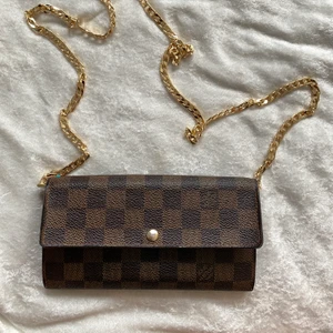 Louis vuitton sarah damier ebene  - Äkta Louis vuitton sarah plånbok damier ebene | med lägg till kedjan (inte från LV) i bra skick | man kan använda som kuvertväska eller axelremväska |knappen kan inte stånga ordenligt, tror det lätt at fixa hos skäddare | koden : CA2008| måttet 19 x 10.5 x 2cm| kommer med louis vuitton påse | kolla gärna på mina andra annonser | följa insta @nmf_se