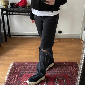 Jeans med slitningar  - Skitsnygga svarttvättade jeans från weekday med egenklippta hål på ena knät. Säljer pga att de har blivit försmå för i midjan, men de passar i längden för mig som är 168 cm lång. Midjemåttet är 24 och längden är 32.