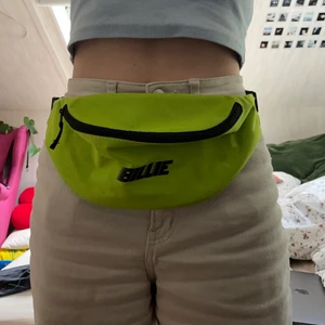 Billie Eilish neon fanny pack - Ett neongult/grönt fanny pack köpt på en Billie Eilish konsert 2019. Går inte att hitta på hennes hemsida längre, kan inte hitta det någon annanstans heller. En stor ficka på framsidan och en på baksidan. Längd på bandet runt höften går att justera. Det är i väldigt fint skick, inte solblekt eller trasigt någonstans. Priset kan diskuteras. Minimum 500kr