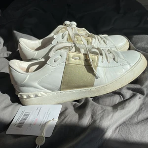 Valentino Garavani skor - Vita valentino sneakers med guld!! Mina favvoskor men dax att sälja 💜 inköpta från Vestiaire collective så äkthesbevis och tag medföljer därifrån 😻 ok skick,  väldigt slitna då de är använda ganska mycket men tycker ändå de har mycket kvar att ge✨ därför säljer jag för ett billigt pris!! Fråga efter fler bilder om ni är osäkra eller annat 💖