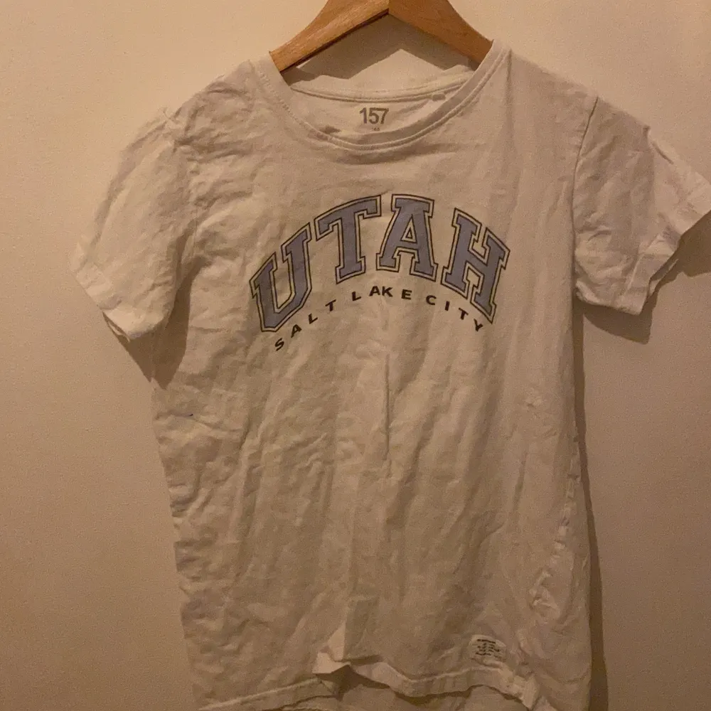  Den är en lång  tröja son Är vit och Det finns en text. T-shirts.