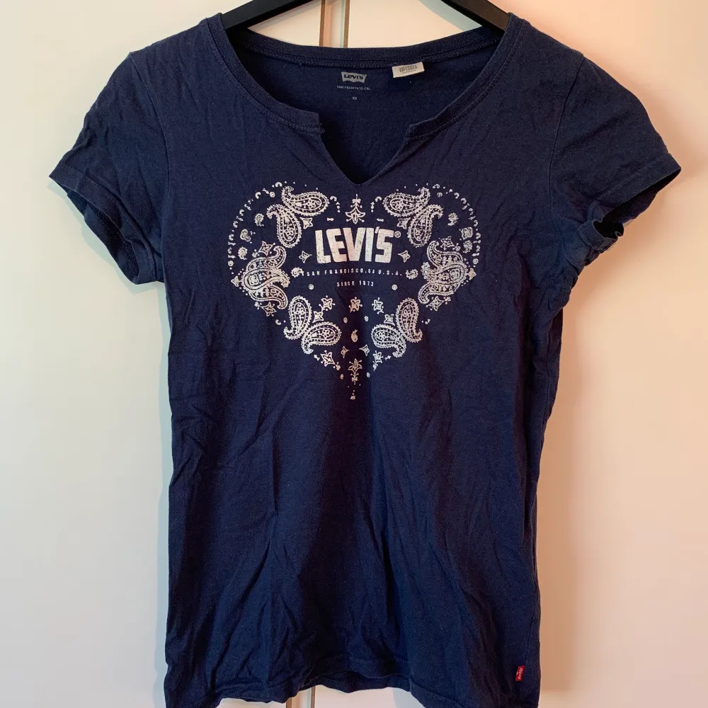 Säljer min Levis t-shirt som är mörkblå med ett jättefint mönster som bildar ett hjärta på bröstet. Strl XS. . T-shirts.