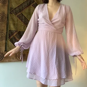 Lila prickig klänning - Jag är ca. 165 cm lång och har storleken XS. Klänningen köptes för ett par månader sedan men användes aldrig. Dragkedjan strular ibland men jag har fixat den. En av bältesslingorna är sönder, men det spelar inte en så stor roll. Bältet går fortfarande att använda. Ärmarna är stora och kan knytas med ett band. 