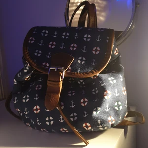 Liten väska med strandigt tema - En liten ryggsäck med havsrelaterat mönster. Rymmer ganska mycket för att vara en sådant liten ryggsäck. Har en liten ficka med dragkedja och är i ett bra tillstånd.