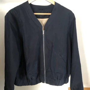 Marinblå bomberjacka - Kort marinblå bomberjacka. Något flammig vid fickan vilket syns på bilden. Lagom boxig på mig som är stl. S-M. Möts i Sthlm eller fraktar. Köparen står för frakt.