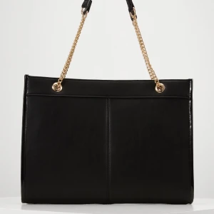 Svart väska  - Helt ny väska. Fick den som present.  Foder : Polyester. Tyg : Skinnimitation. Höjd : 27 cm. Längd : 38cm. Vidd : 7cm. Handtag : 28cm.  🤍🤍