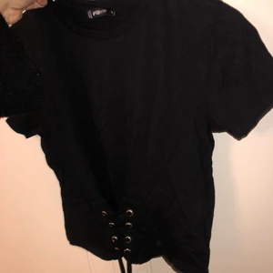 Topp - Svart topp med snörning vid midjan. 