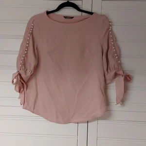 Ljusrosa blus  - Söt ljusrosa blus med pärlor pch knäppa på ärmarna. Ärmarna är i trekvartslängd. Aldrig använd, endast provad  