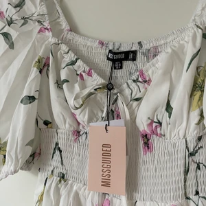 Blommig klänning - Helt ny klänning från Missguided som tyvärr inte passar mig. Storlek 32. Prislappen sitter kvar. Köpt för 400kr