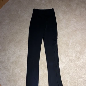 Byxor med slits - Ett par sjukt snygga svarta byxor med slits. Från NELLY och är i storlek S. Skulle även kunna passa Xs o M beroende på kroppsform och hur man vill att de ska sitta. Säljs då de inte kommer till användning 