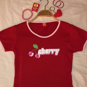 cherry top🍒 - supersöt y2k top med super sött ”cherry” tryck i olika färger och glitter. jättebra skick i stretchigt material, användes av min storasyster 2002. detta är en barn tröja i barn storlek men skulle passa som en magtröja för någon med A kupa/liten B kupa. buda? vet ej vad jag ska sätta för pris 🍒❤️
